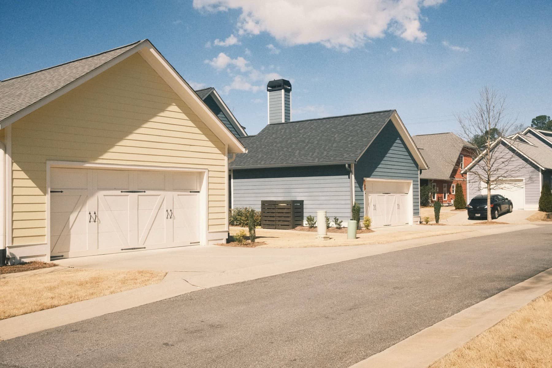 Concrete driveway aprons meeting a residential street lined with two-car garages, Lake Lanier area