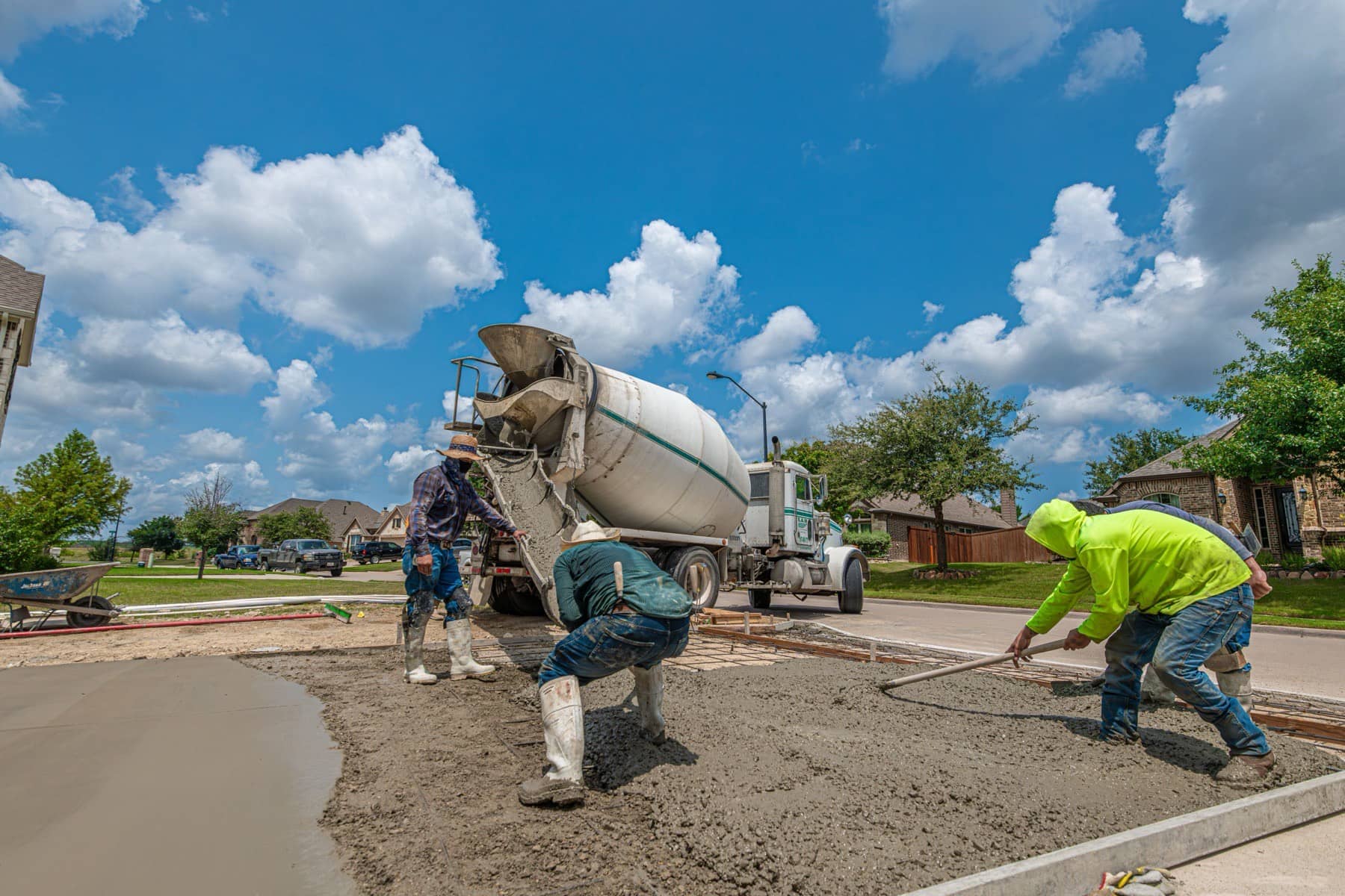 Ready-mix truck pouring concrete into driveway forms over steel reinforcement on a residential street, Lake Lanier area